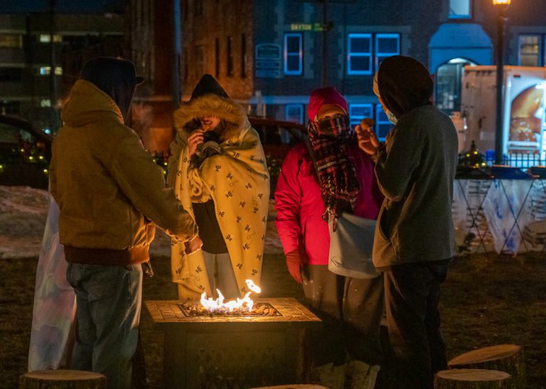 Christmas Market. group arnd fire w. blankets
